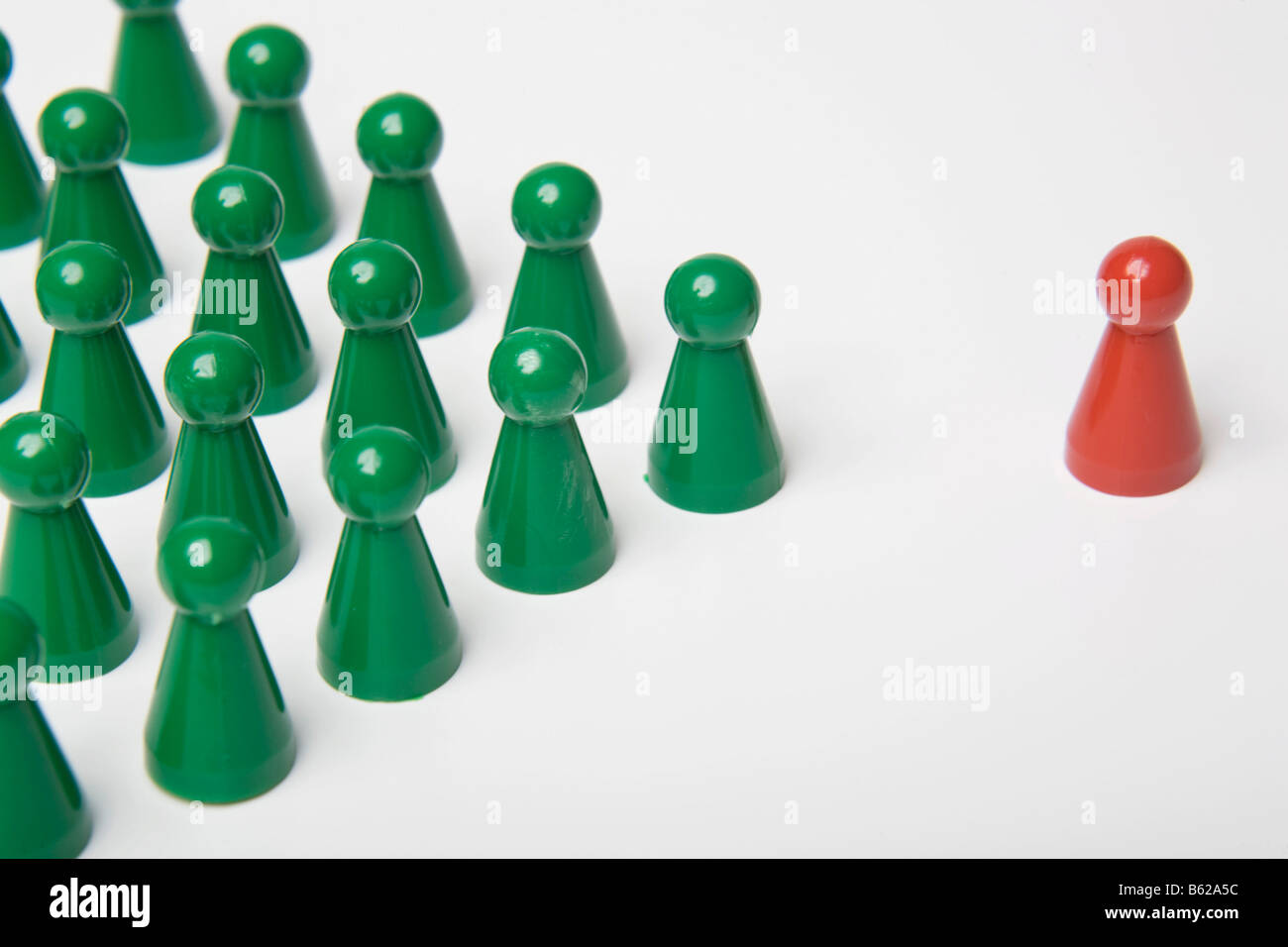 Pièces de jeu Vert debout à côté d'une seule pièce de jeu rouge, symbolique du leadership Banque D'Images