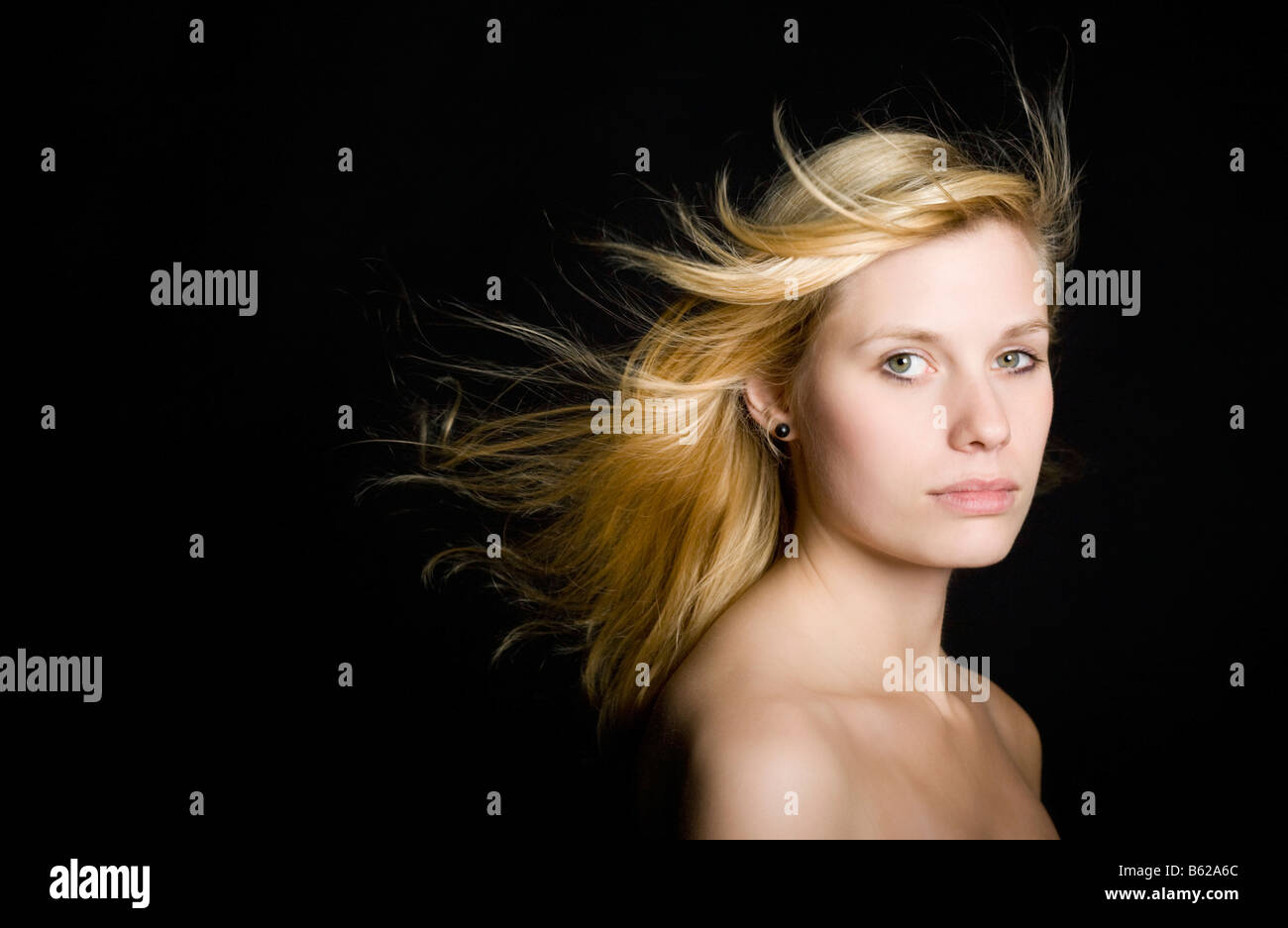 Jeune femme blonde avec de longs cheveux de soufflage in front of black Banque D'Images