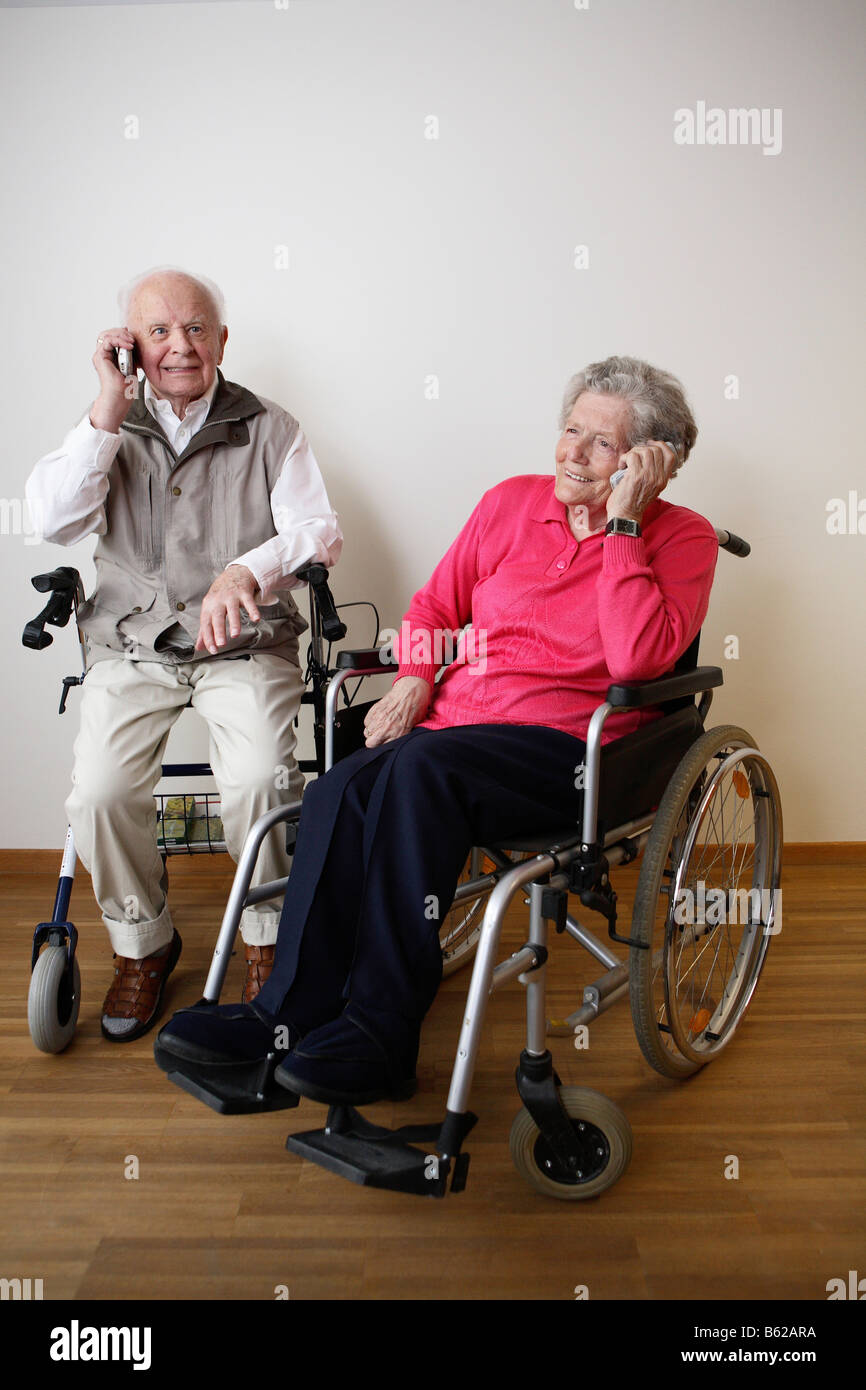 Les personnes âgées en fauteuil roulant sur leurs téléphones portables Banque D'Images