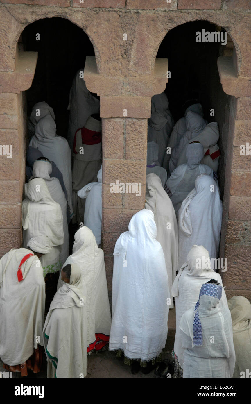 Les femmes orthodoxes éthiopiennes portant des capes blanc à l'entrée de l'église monolithique Beta Medhane Alem, Lalibela, Éthiopie, Af Banque D'Images