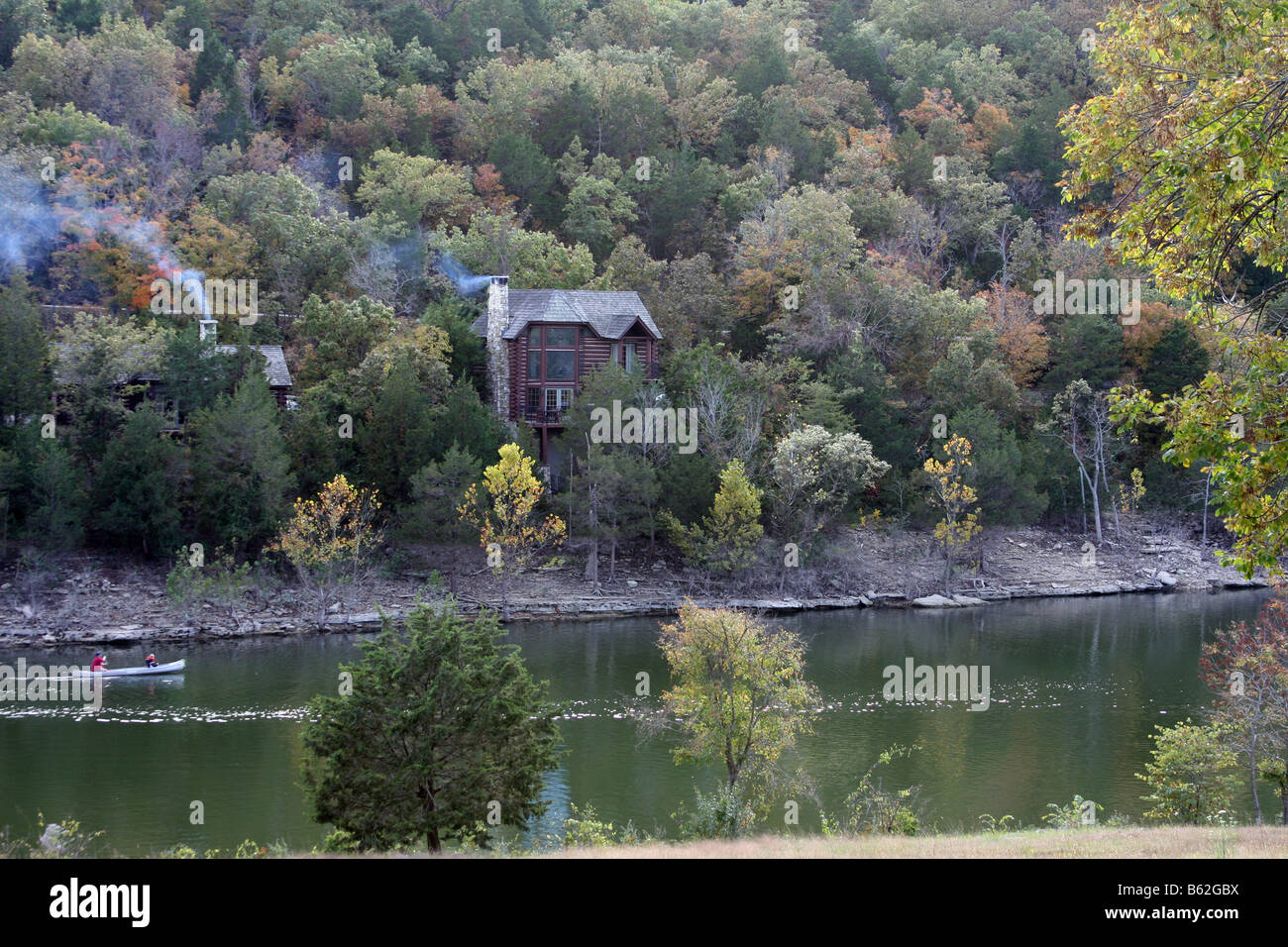 Rustic Log cabins dans le feuillage d'automne des collines du Missouri avec un canot dans le lac ci-dessous Banque D'Images