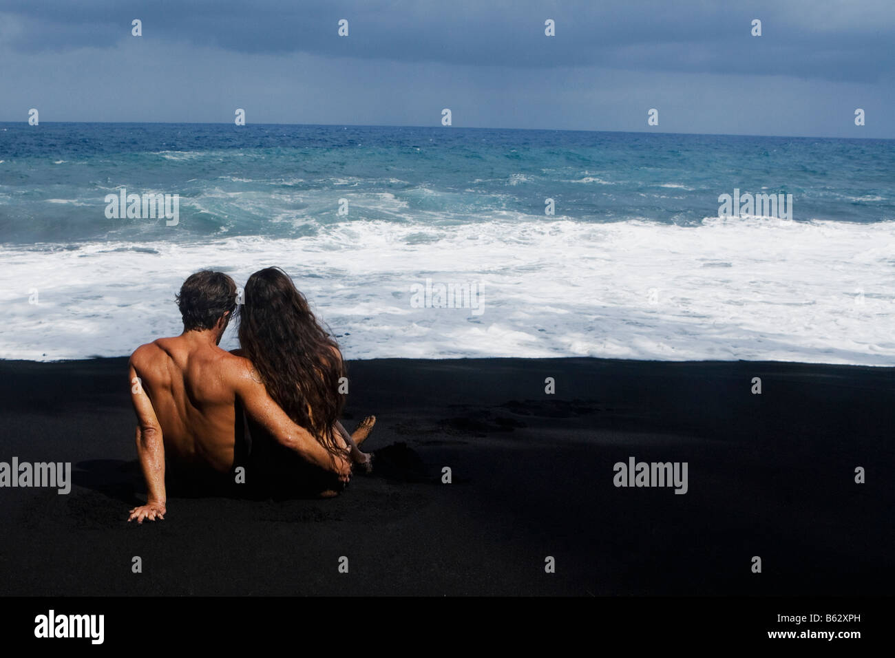 Vue arrière d'un couple assis sur la plage, Kehena Beach, Big Island, Hawaii, USA Banque D'Images