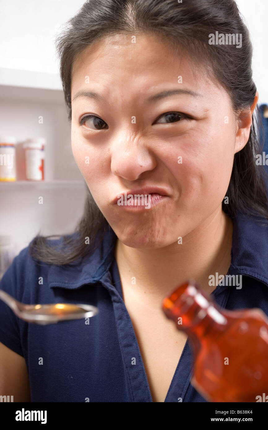Femme à la maison n'aime pas prendre du sirop contre la toux. Banque D'Images