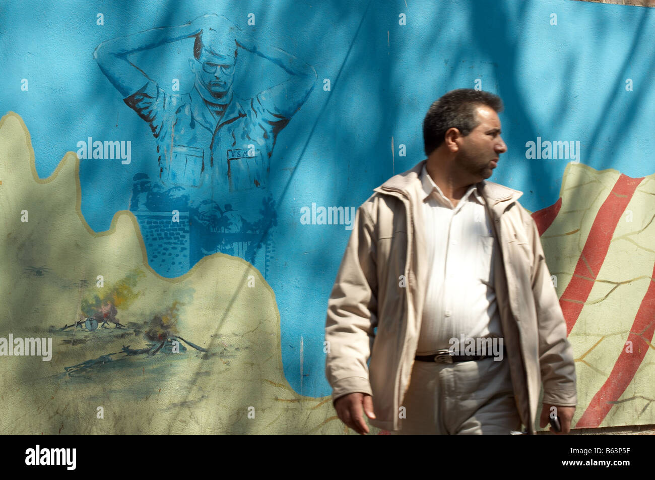 Un homme debout devant un tableau d'un otage américain sur les murs extérieurs de l'ex ambassade des États-Unis à Taleghani Street Banque D'Images