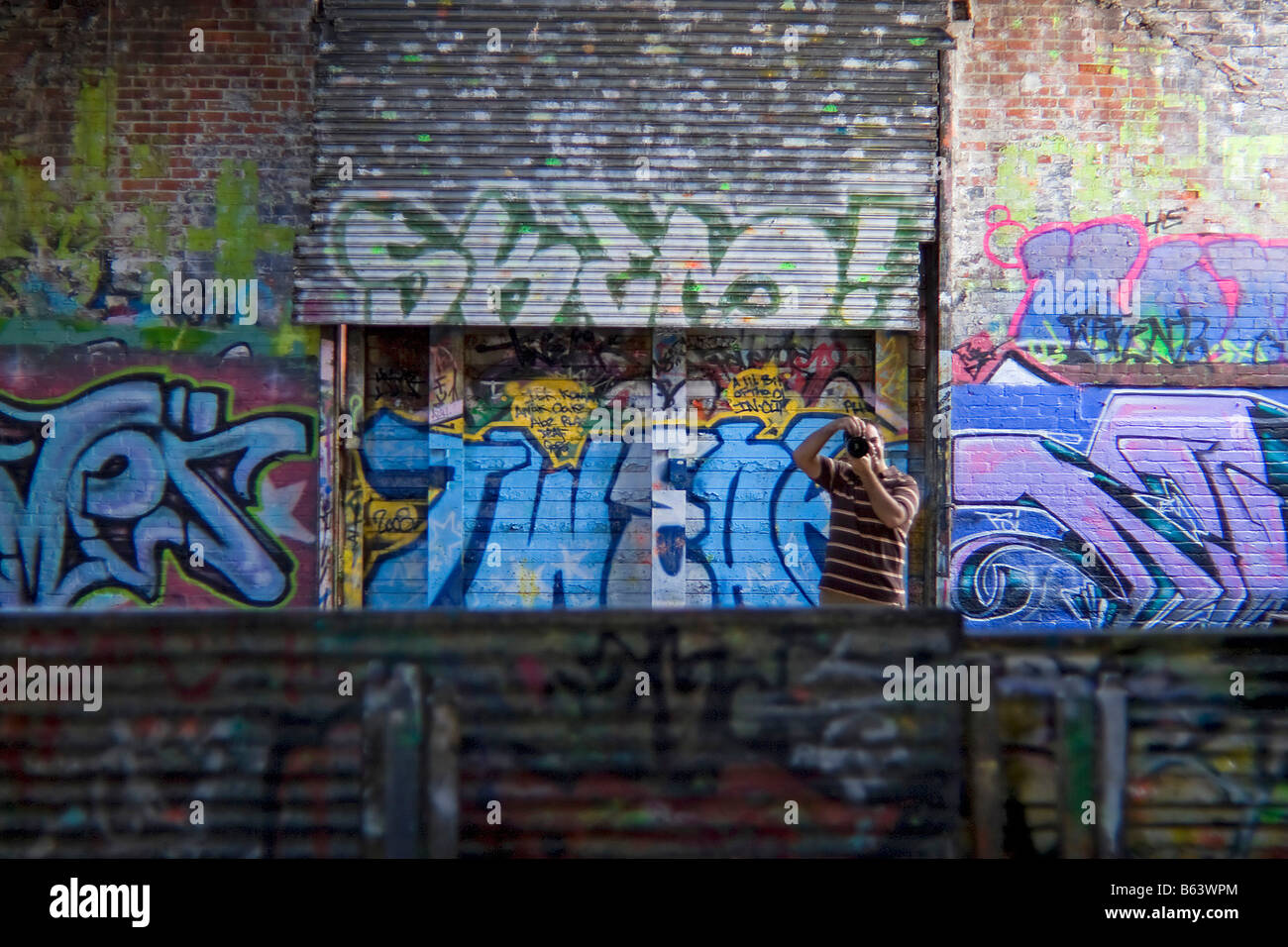 Un photographe prise de vue dans un domaine couvert de graffitis Banque D'Images