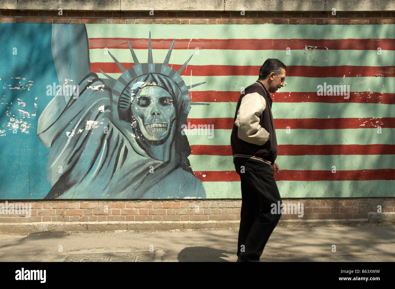 Un homme passe devant une fresque de propagande anti-américaine représentant une statue de la liberté à visage de crâne et des bandes du drapeau américain à l'ancienne ambassade américaine à Téhéran. Banque D'Images