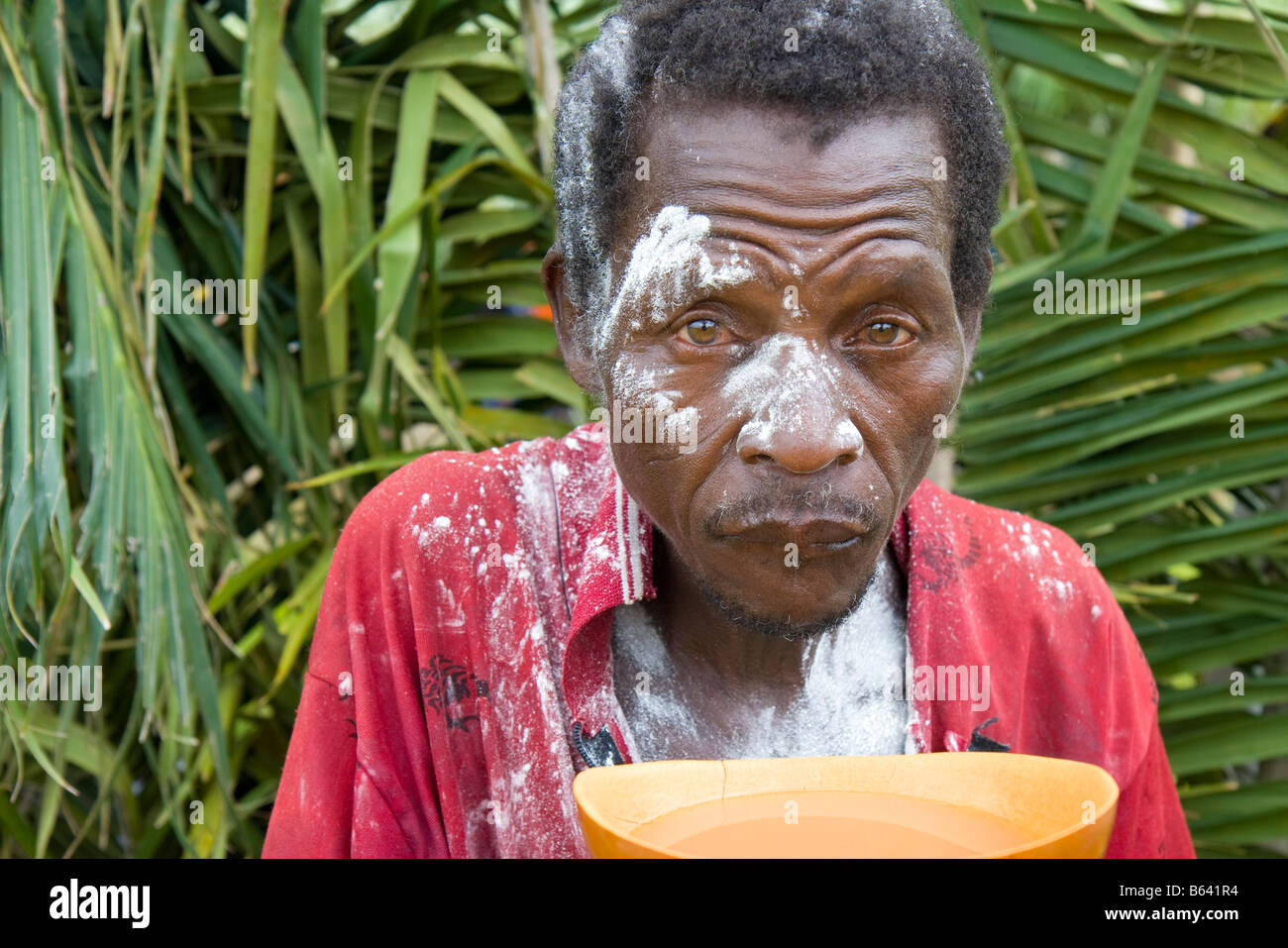 Un homme couvert de talc en poudre (en indiquant qu'il a déjà été lancé), des boissons du vin de palme au cours de la Festival Evala au Togo. Banque D'Images