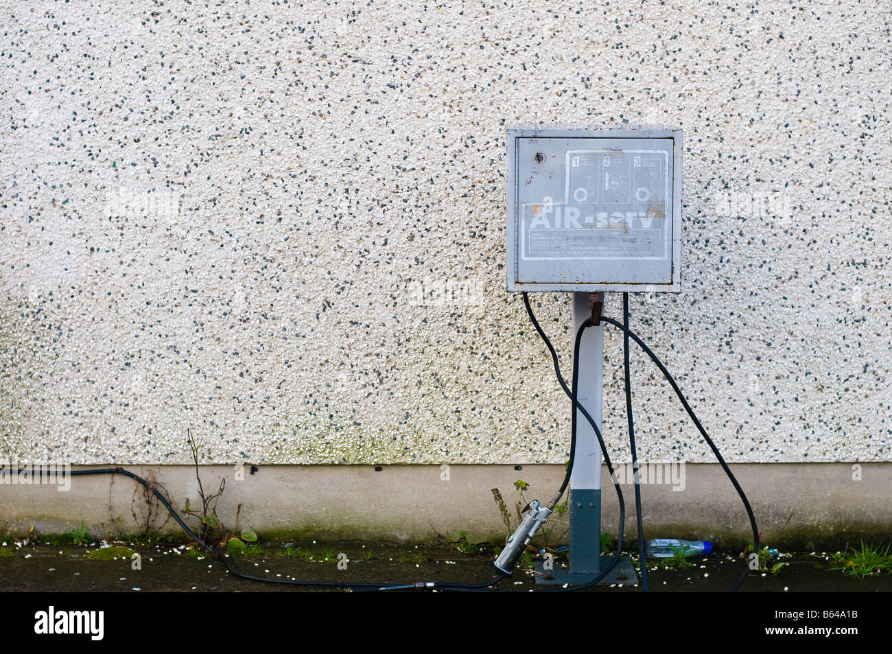 Gonfleur/pompe à air au garage, contre un caillou-mur en pointillés. Banque D'Images