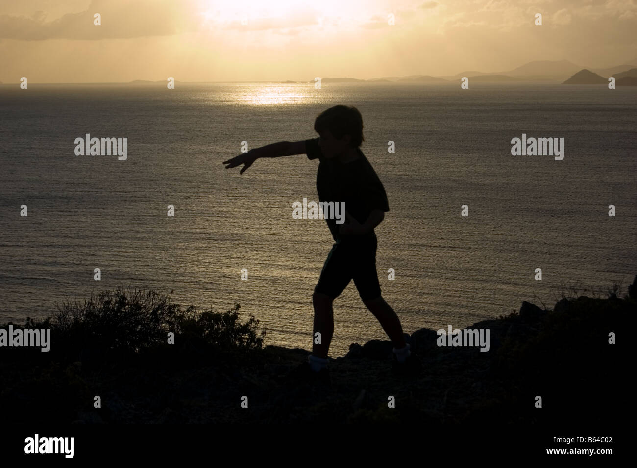 Silhouette de garçon en train de lancer un rocher St. John USVI Banque D'Images