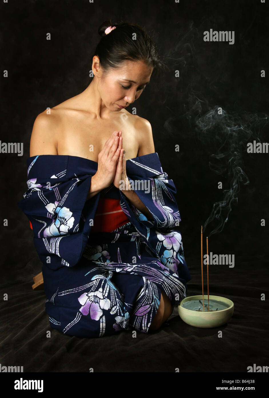 Femme japonaise dans un kimono bleu, s'agenouiller et prier Banque D'Images