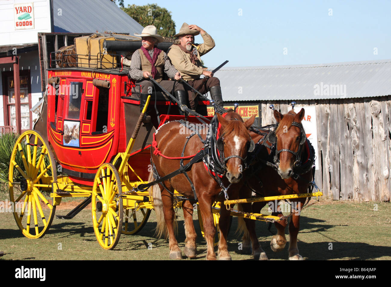 Deux cowboys conduisant le Butterfield Overland Stage Coach à travers une vieille ville de l'ouest Banque D'Images