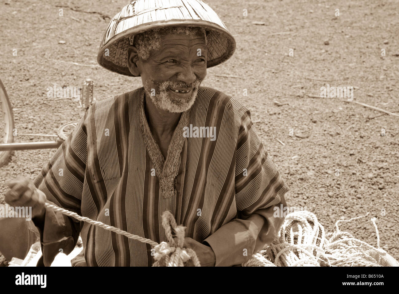 Un vieil homme Peul se trouve en face du marché des animaux à Kaya, Burkina Faso le tissage d'acier qu'il vend à l'marketgoers. Banque D'Images