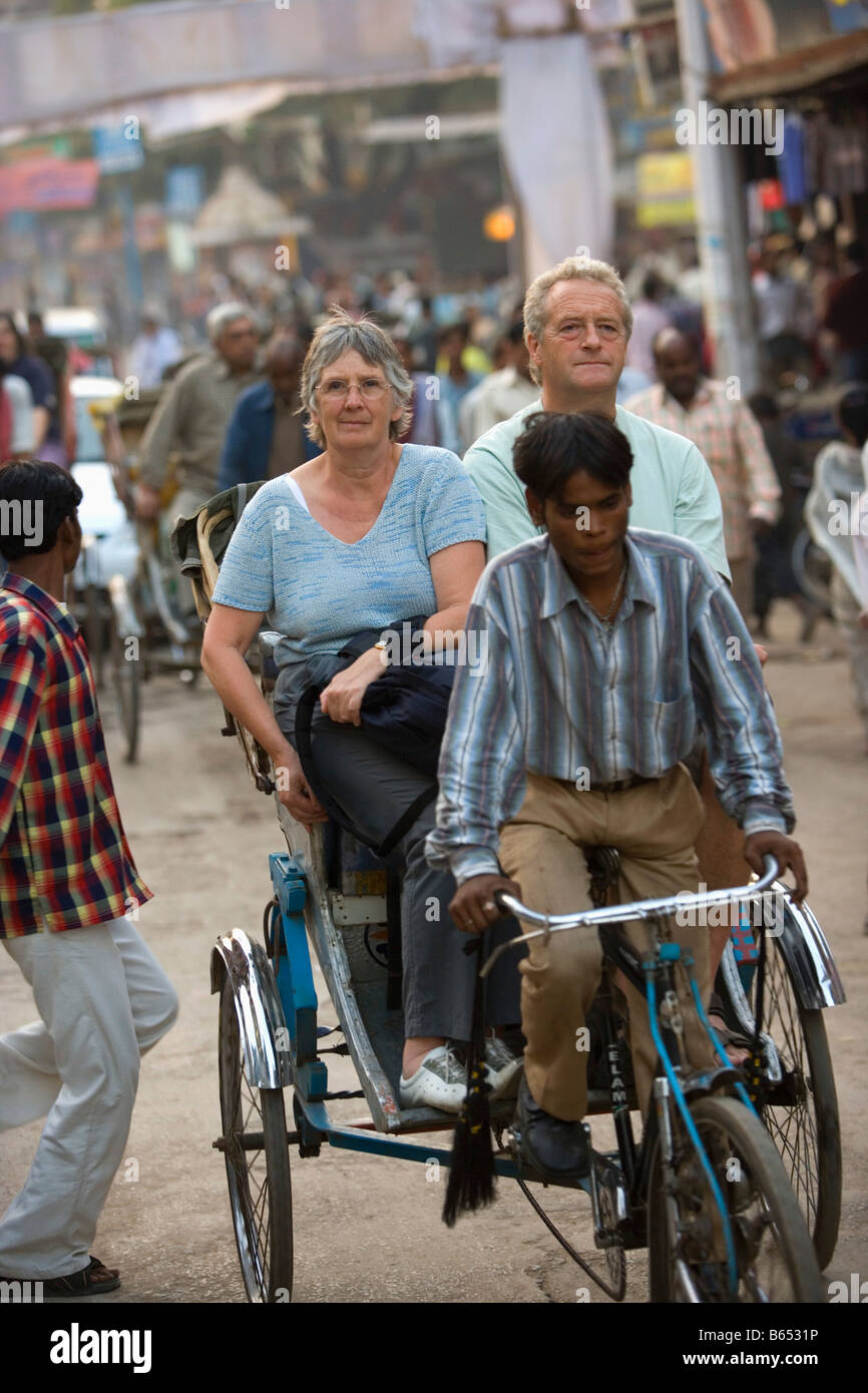 L'Inde, Uttar Pradesh, Varanasi, scène de rue. Couple de touristes dans pedicap ou pousse-pousse à vélo. Banque D'Images