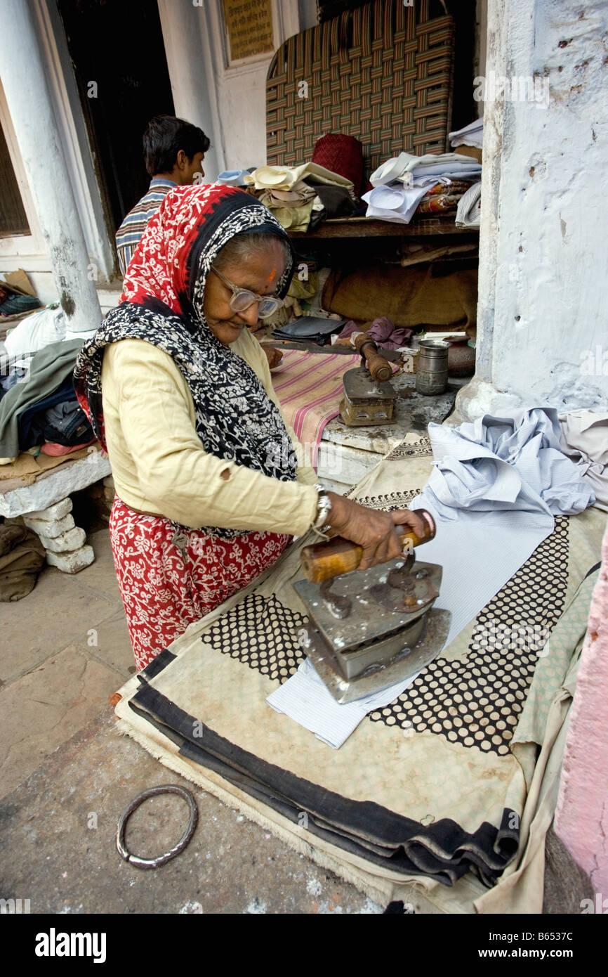 L'Inde, Uttar Pradesh, Varanasi, scène de rue. Vieille Femme le repassage. Banque D'Images