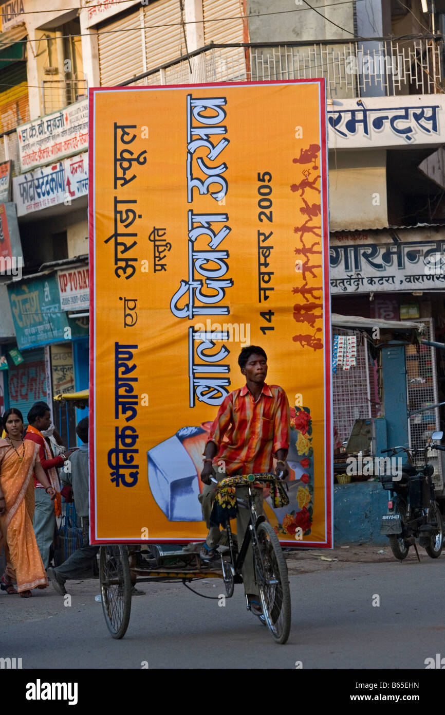 L'Inde, Uttar Pradesh, Varanasi, scène de rue. Transport de l'homme cycle rickshaw ou billboard dans pedicap. Banque D'Images