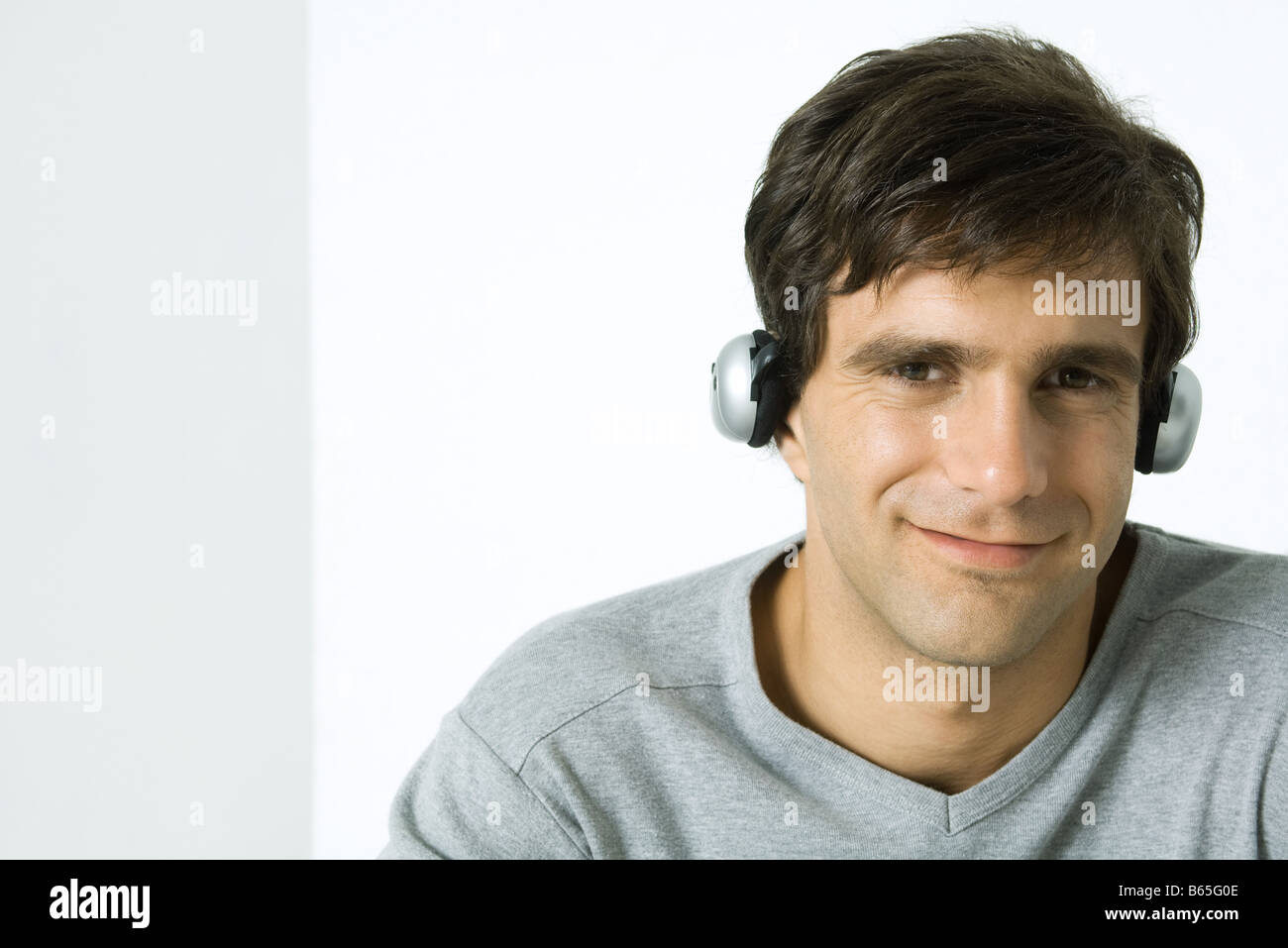Man listening to headphones, smiling at camera Banque D'Images