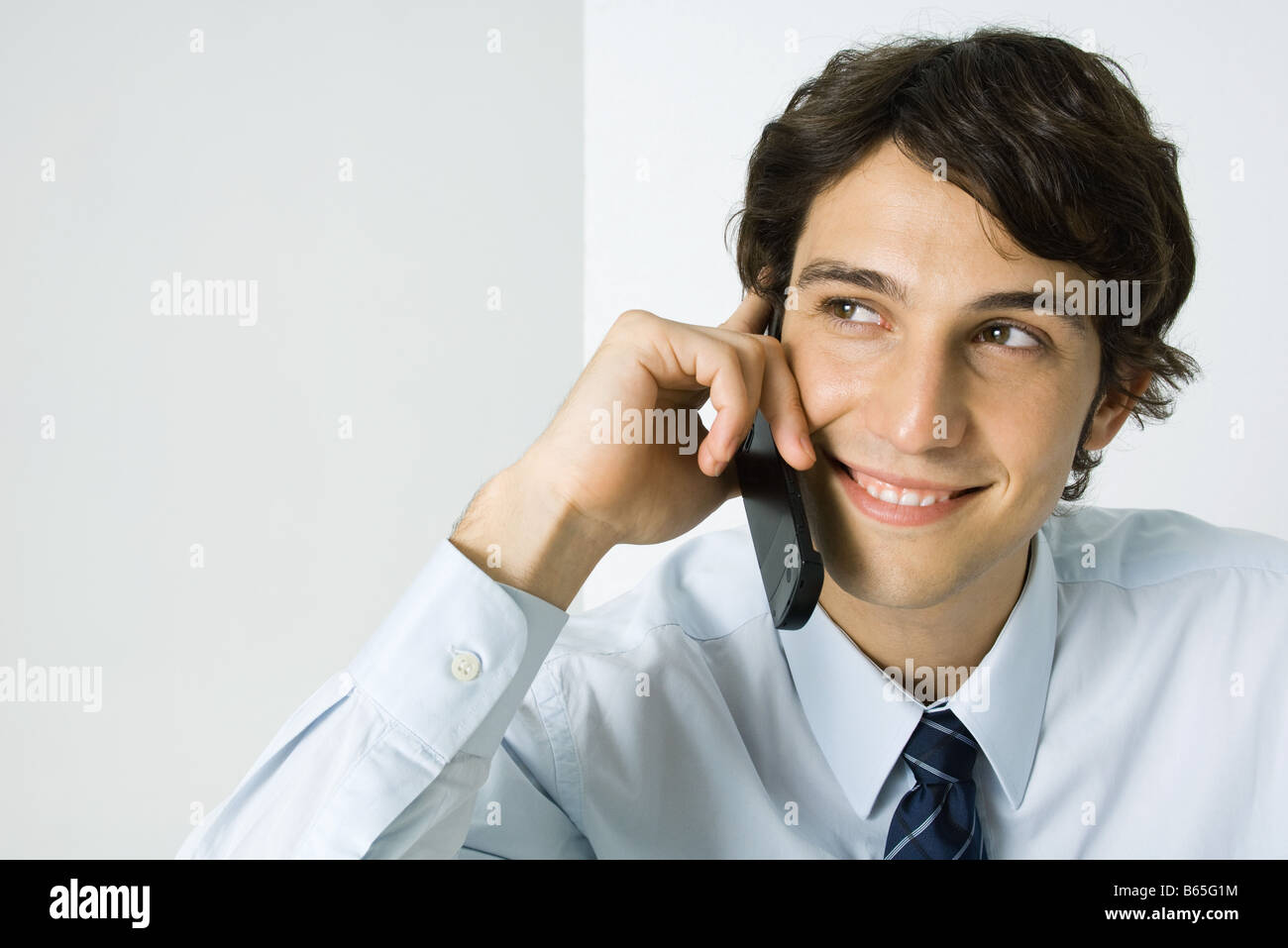 Young man using cell phone, smiling, Portrait Banque D'Images