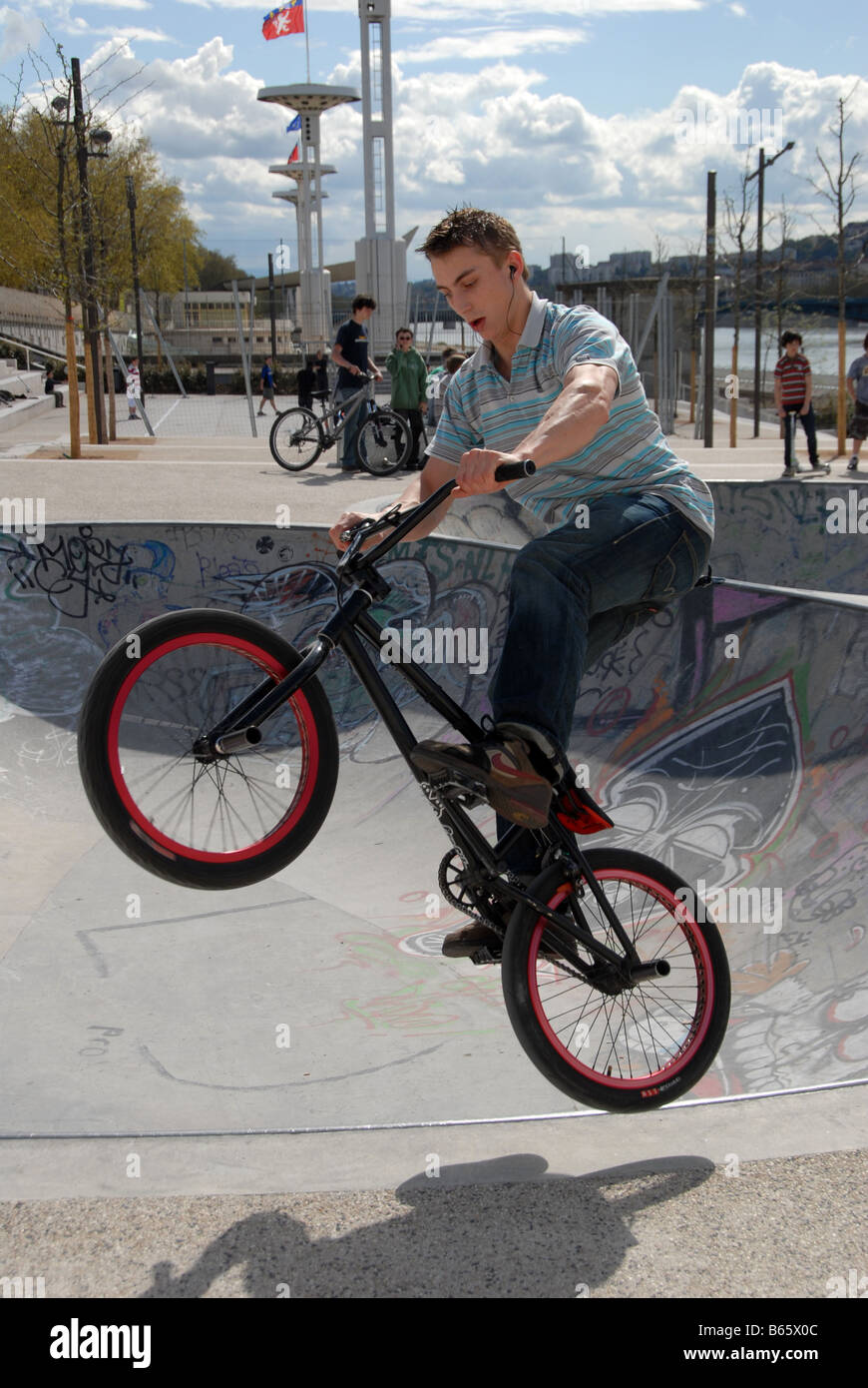 Un jeune garçon bondit en l'air sur son vélo BMX dans un parc de skate dans le centre-ville de Lyon, France Banque D'Images
