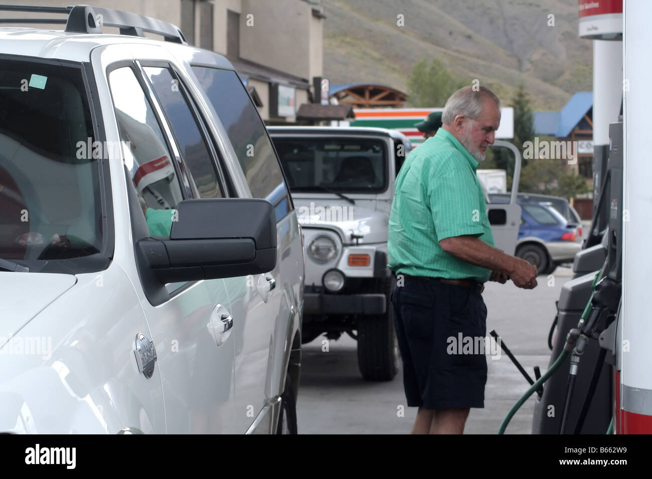 Un homme à la station de gaz remplissant un véhicule SUV Banque D'Images