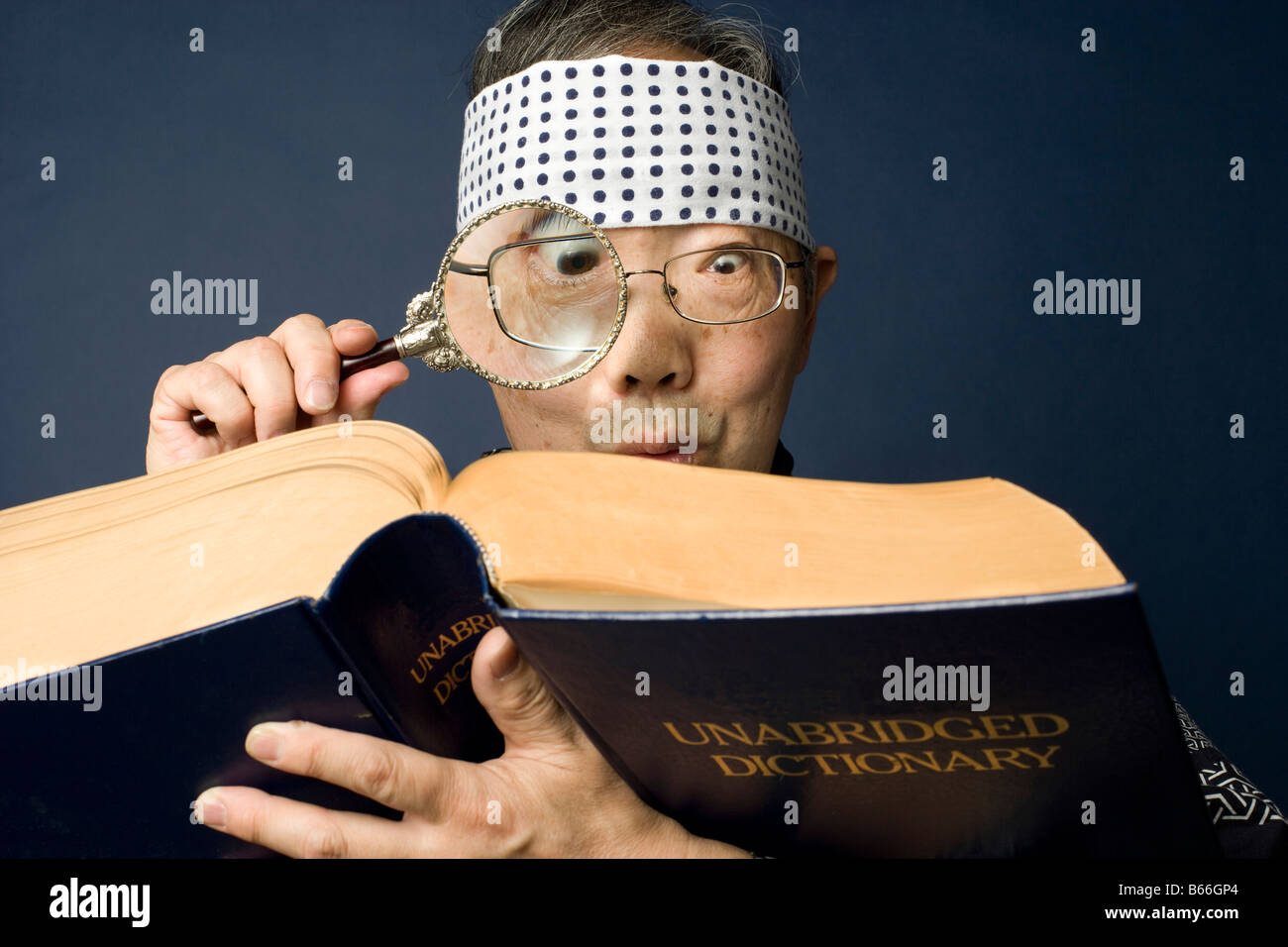 Japonais Senior homme portant un costume traditionnel utilise une loupe pour lire un dictionnaire Banque D'Images