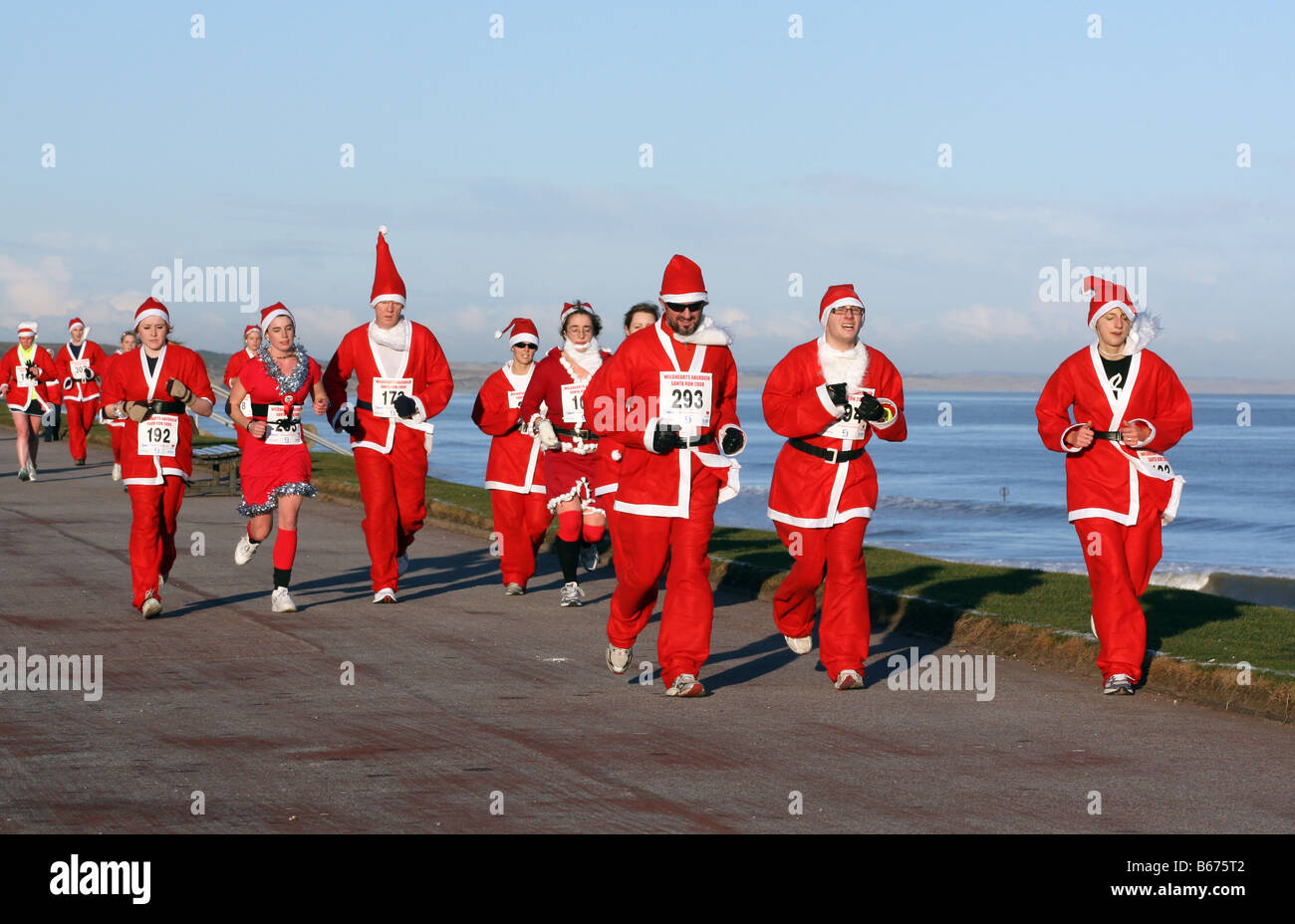Line up de Santas portant les costumes de Noël de père rouge prenant part à santa annuel courir le long de la plage à Aberdeen, Écosse Royaume-Uni Banque D'Images