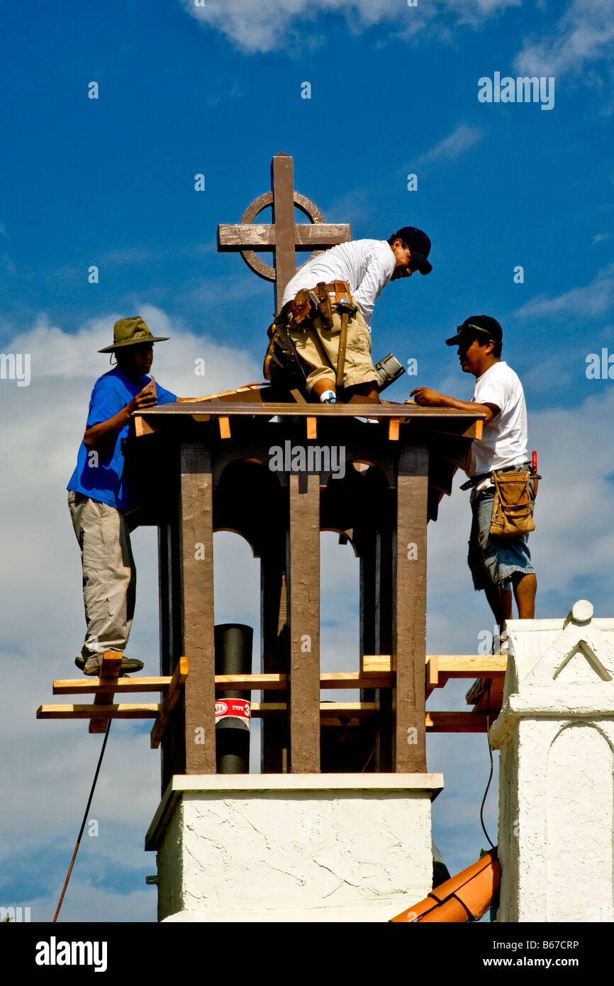 Ouvriers hispaniques se préparer à le remplacer de la couverture de toit clocher d'une église catholique dans Laguna Beach CA Banque D'Images
