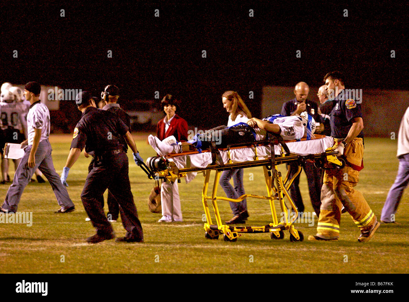 Joueur de football de l'école secondaire blessé à roues est sur le terrain par les ambulanciers lors d'un jeu de nuit dans le sud de la Californie Banque D'Images