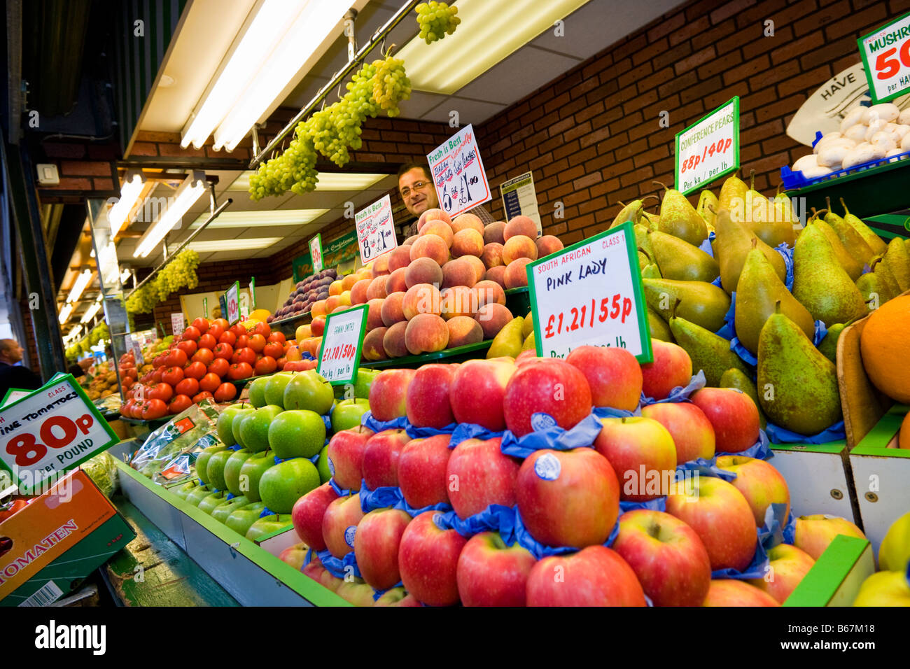 Vendeur lors d'une échoppe de marché vendant des fruits et légumes frais, UK Banque D'Images