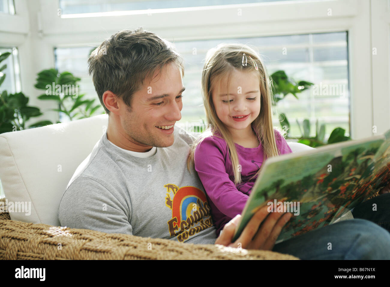 Père et fille (3-4 ans) la lecture d'un livre, Munich, Allemagne Banque D'Images