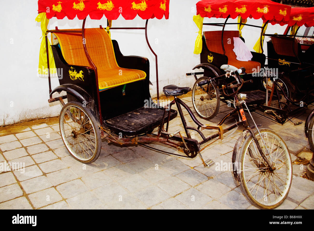 Des vélotaxis devant un mur, Qufu, dans la province de Shandong, Chine Banque D'Images