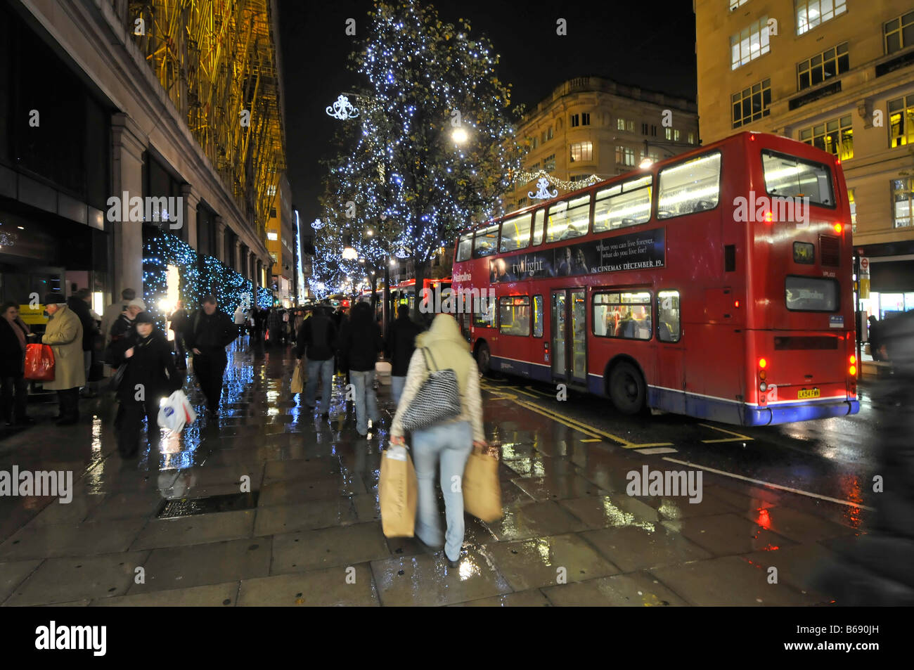 Oxford Street entre les consommateurs et les décorations de Noël et London Bus dans la pluie à l'extérieur du magasin Selfridges Banque D'Images