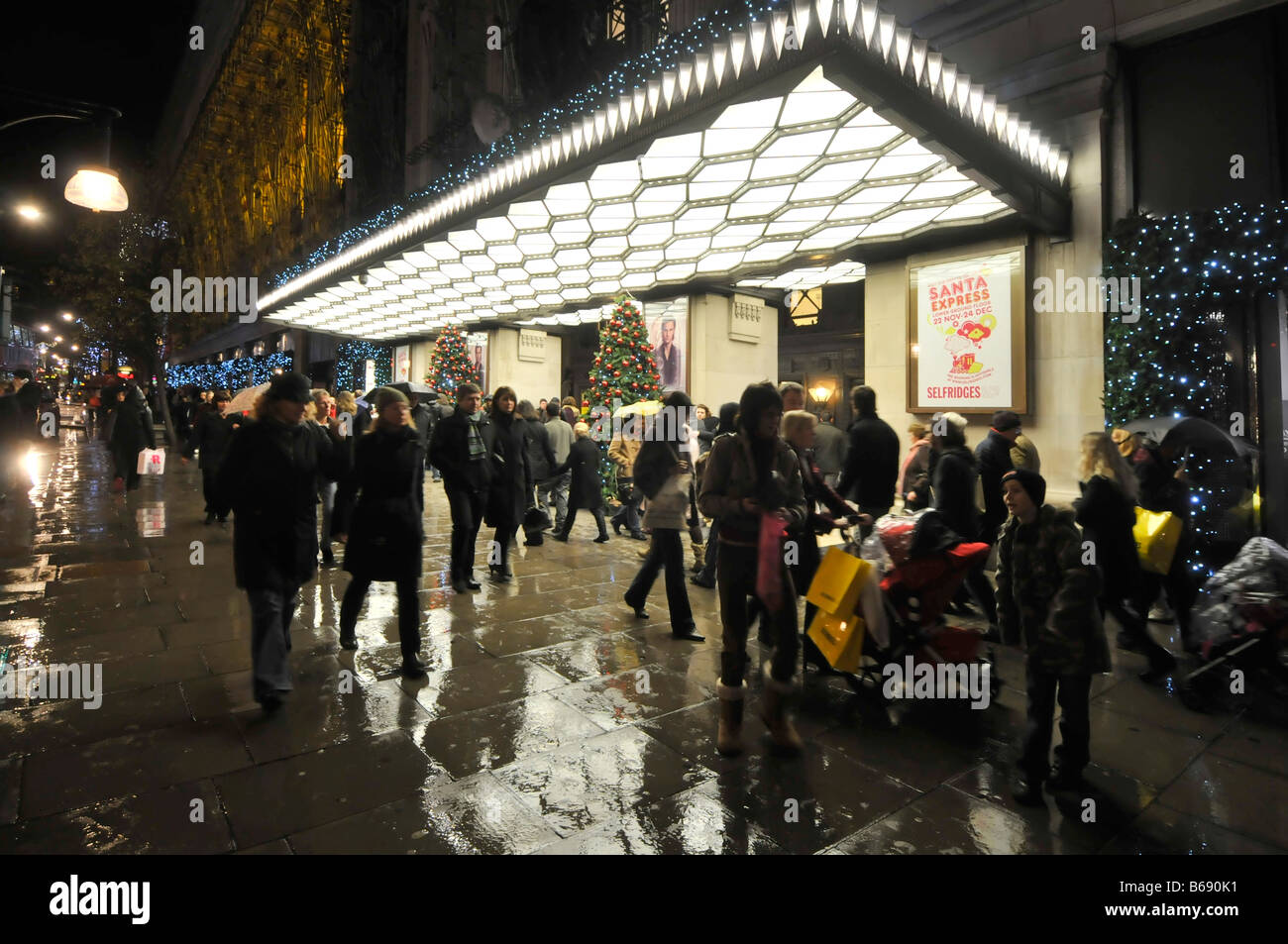 Vue de nuit les amateurs de shopping et de touristes se sont affairés à Oxford Street et les magasins de Noël sous la pluie, à l'extérieur du grand magasin Selfridges, à l'entrée de Londres Banque D'Images