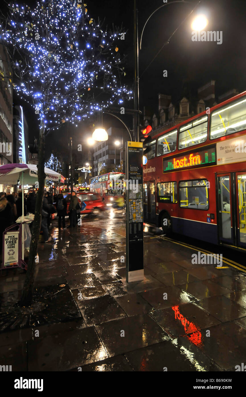 Oxford street Shopping et décorations de Noël panneau publicitaire lumineux London bus sous la pluie Banque D'Images