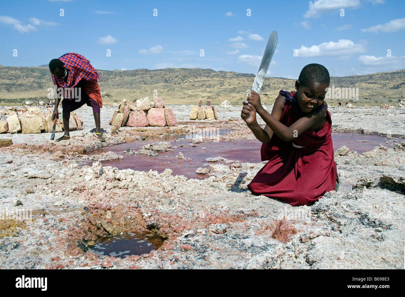 L'extraction de la soude au lac Natron en Tanzanie Une jeune fille Massaï dalles coupe de sel avec une machette Banque D'Images