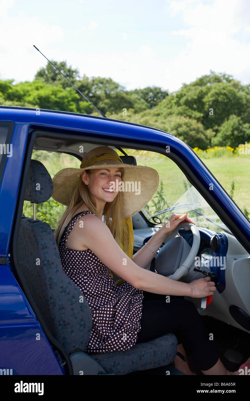 Jeune femme à la roue de la voiture électrique Banque D'Images