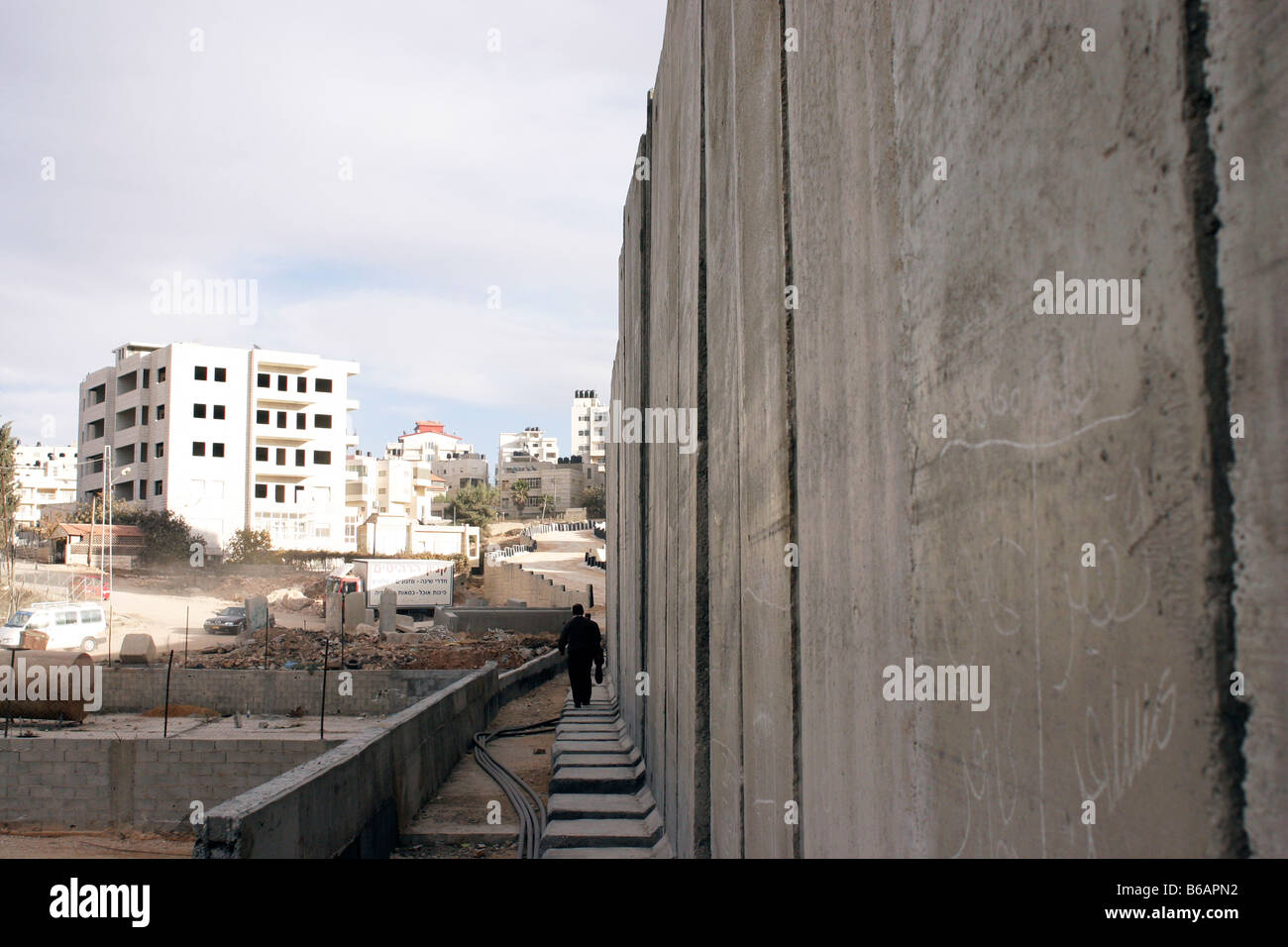 Un homme marche palestinienne par le mur de séparation inachevée dans les territoires occupés de Cisjordanie ville de Al-Ram, Palestine Banque D'Images