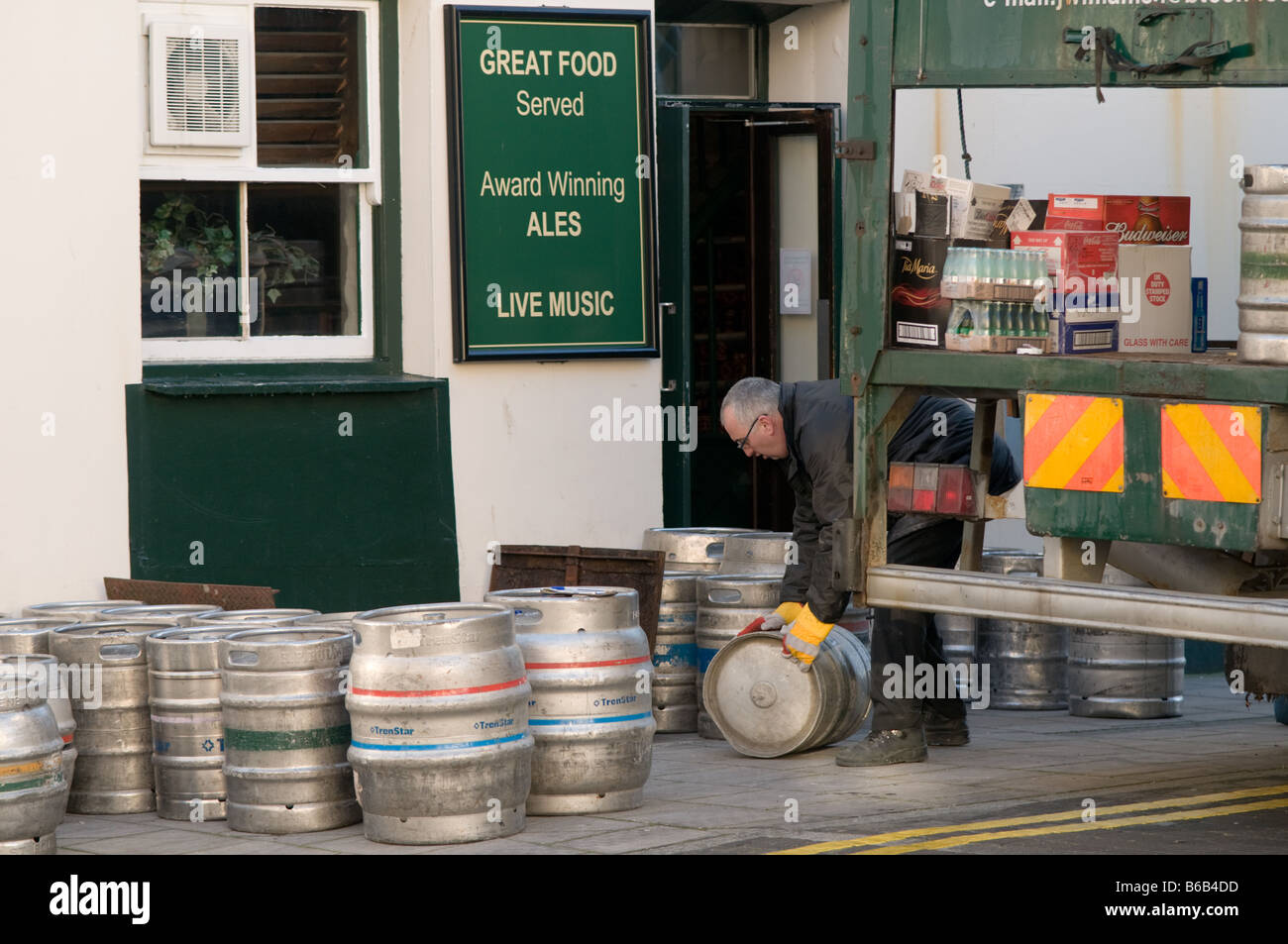 Un homme le roulement d'un fût de bière en fût d'un pub offrant la charge hebdomadaire d'alcool Aberystwyth Wales UK Banque D'Images