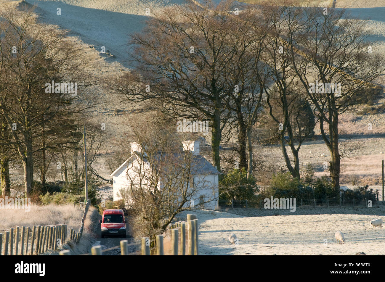 Bureau de poste rouge van de livraison de courrier portant à une maison rurale isolée sur un matin d'hiver près de Pontrhydygroes Mid Wales UK Banque D'Images