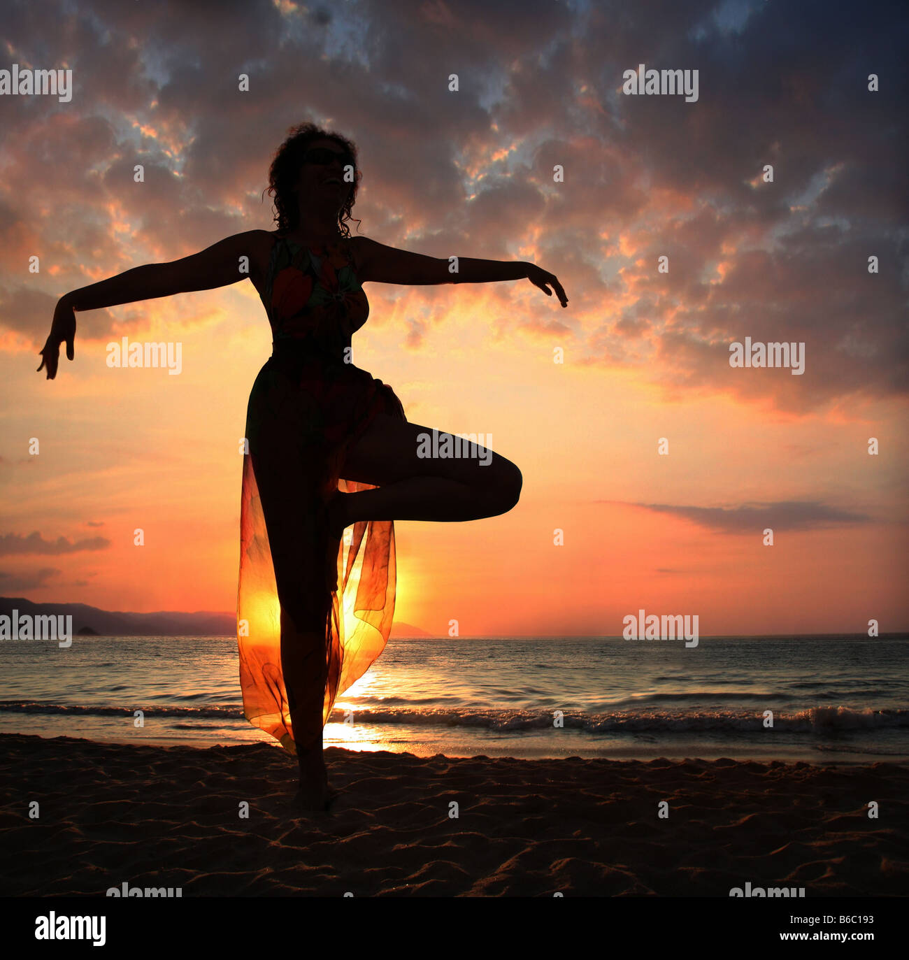 Woman doing yoga exercice sur la plage au coucher du soleil d'ossature Banque D'Images