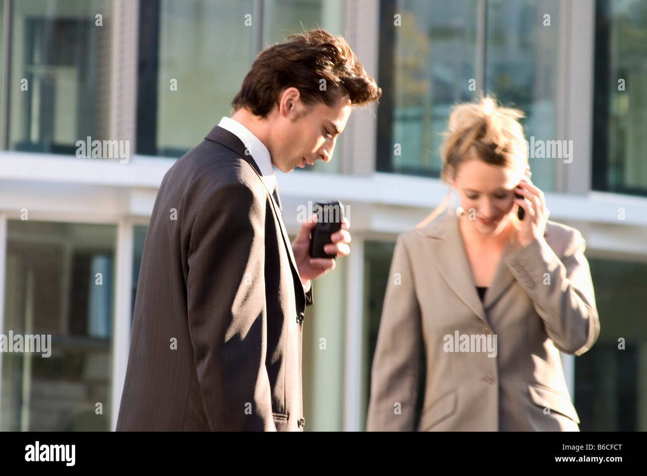 Businessman and businesswoman using mobile phones Banque D'Images