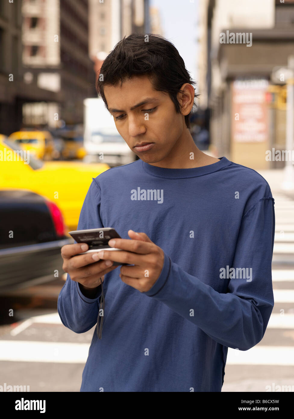 Indian man text messaging on city street Banque D'Images