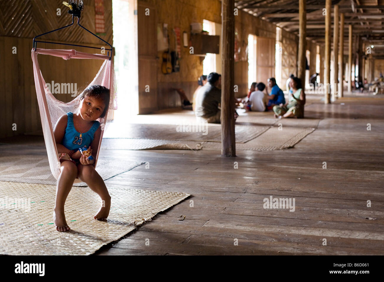 Iban girl sitting on swing dans le couloir, Iban, Bornéo, Indonésie Banque D'Images