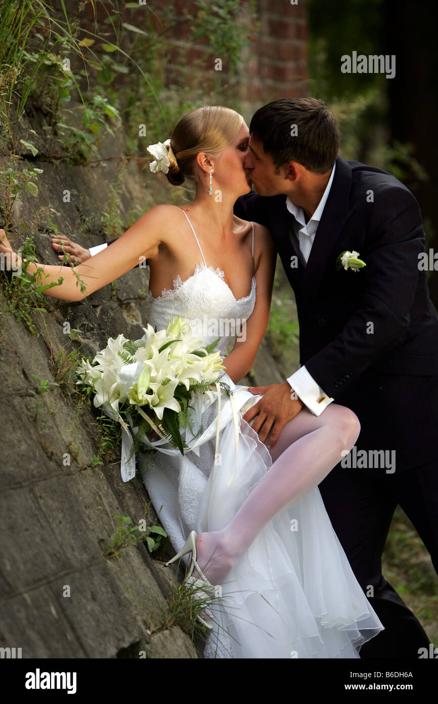 Kissing young woman leaning against wall in countryside Banque D'Images