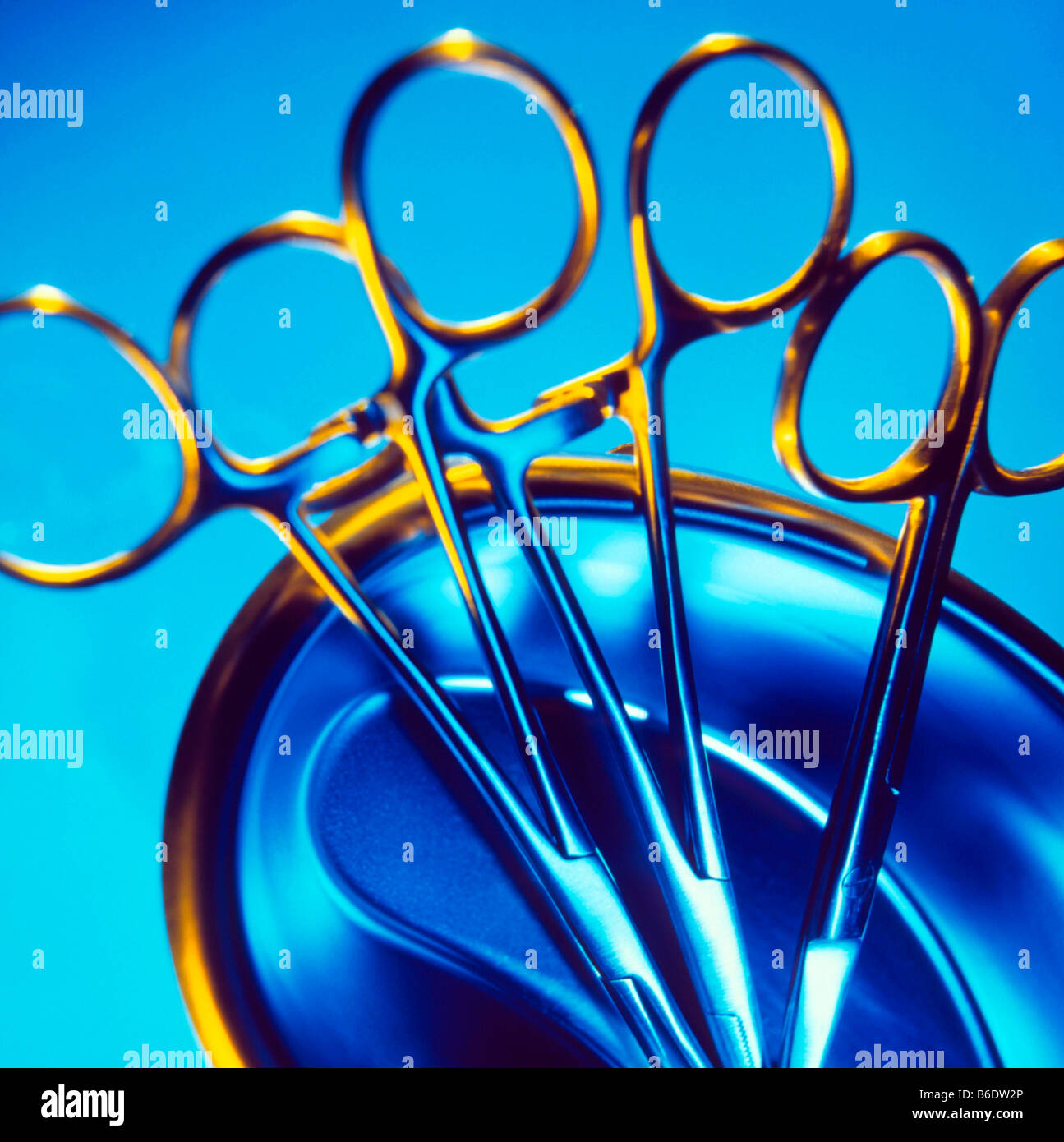 Des pinces et des ciseaux. Deux paires de pinces chirurgicales et d'une paire de ciseaux en forme de rein dans un bol en acier inoxydable. Banque D'Images