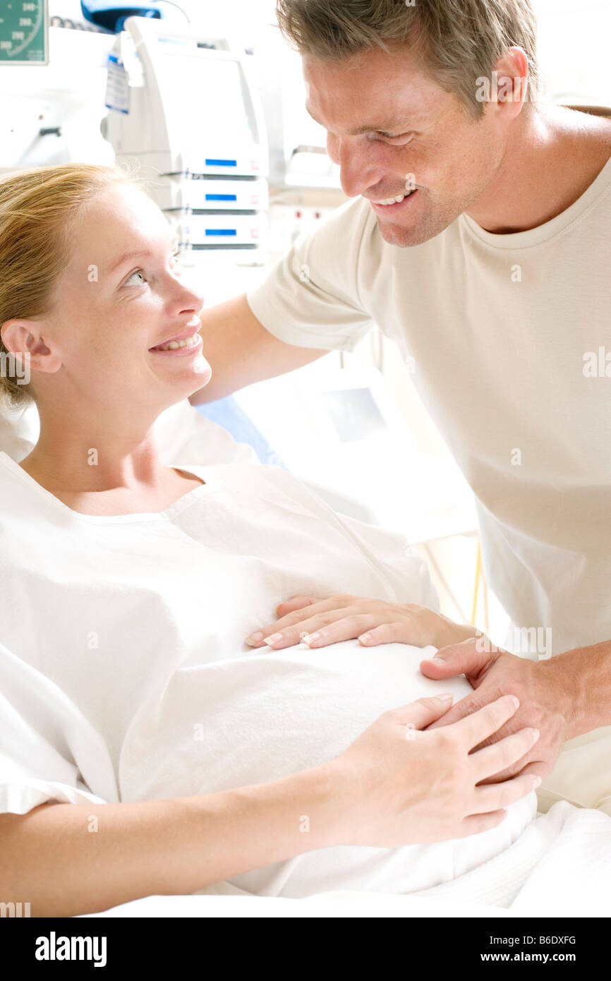 Pregant woman dans un lit d'hôpital à la recherche de son partenaire. Banque D'Images