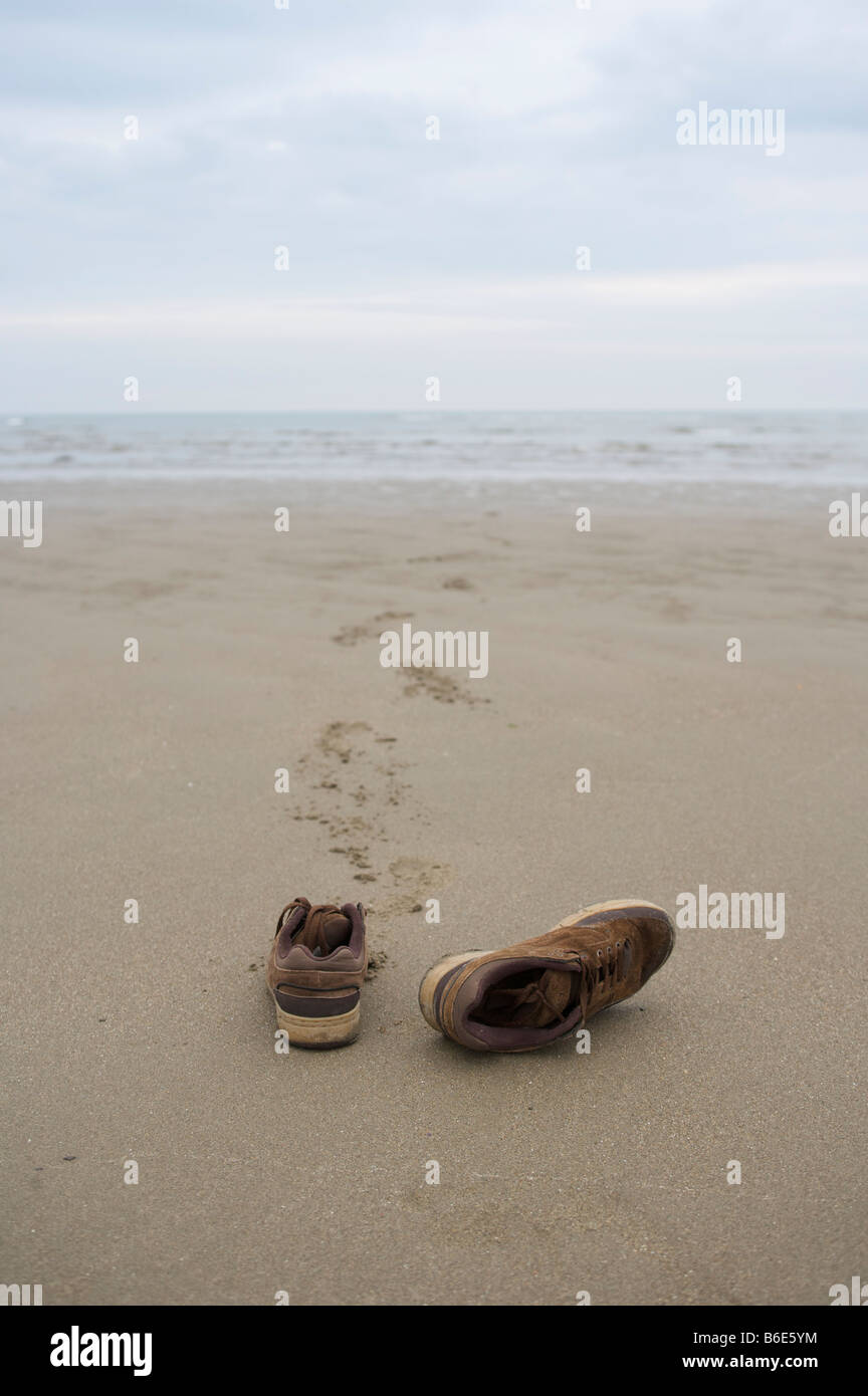 Gauche chaussures sur une plage, sables bitumineux poppit, Pays de Galles, Royaume-Uni. Banque D'Images