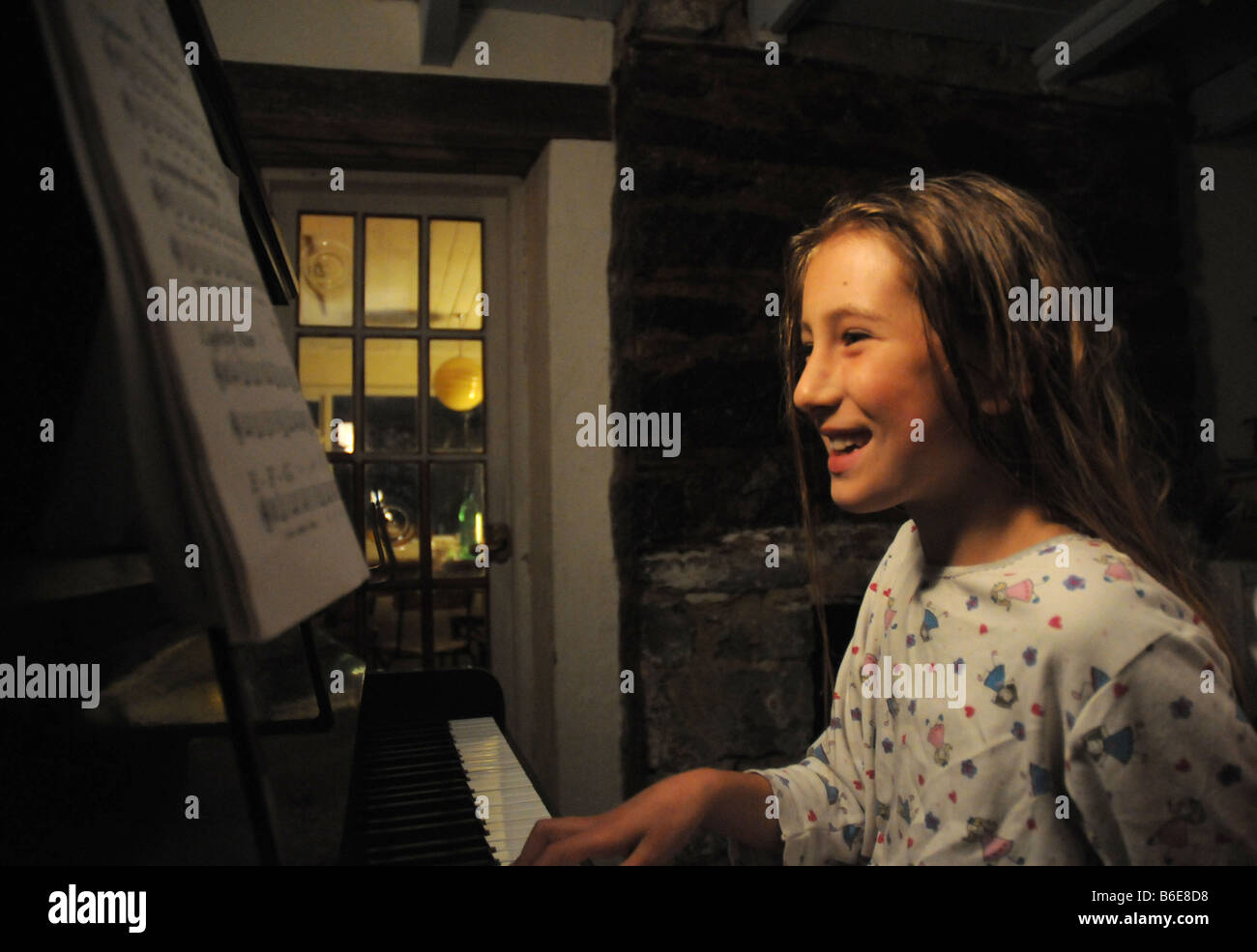 Girl playing piano, smiling Banque D'Images
