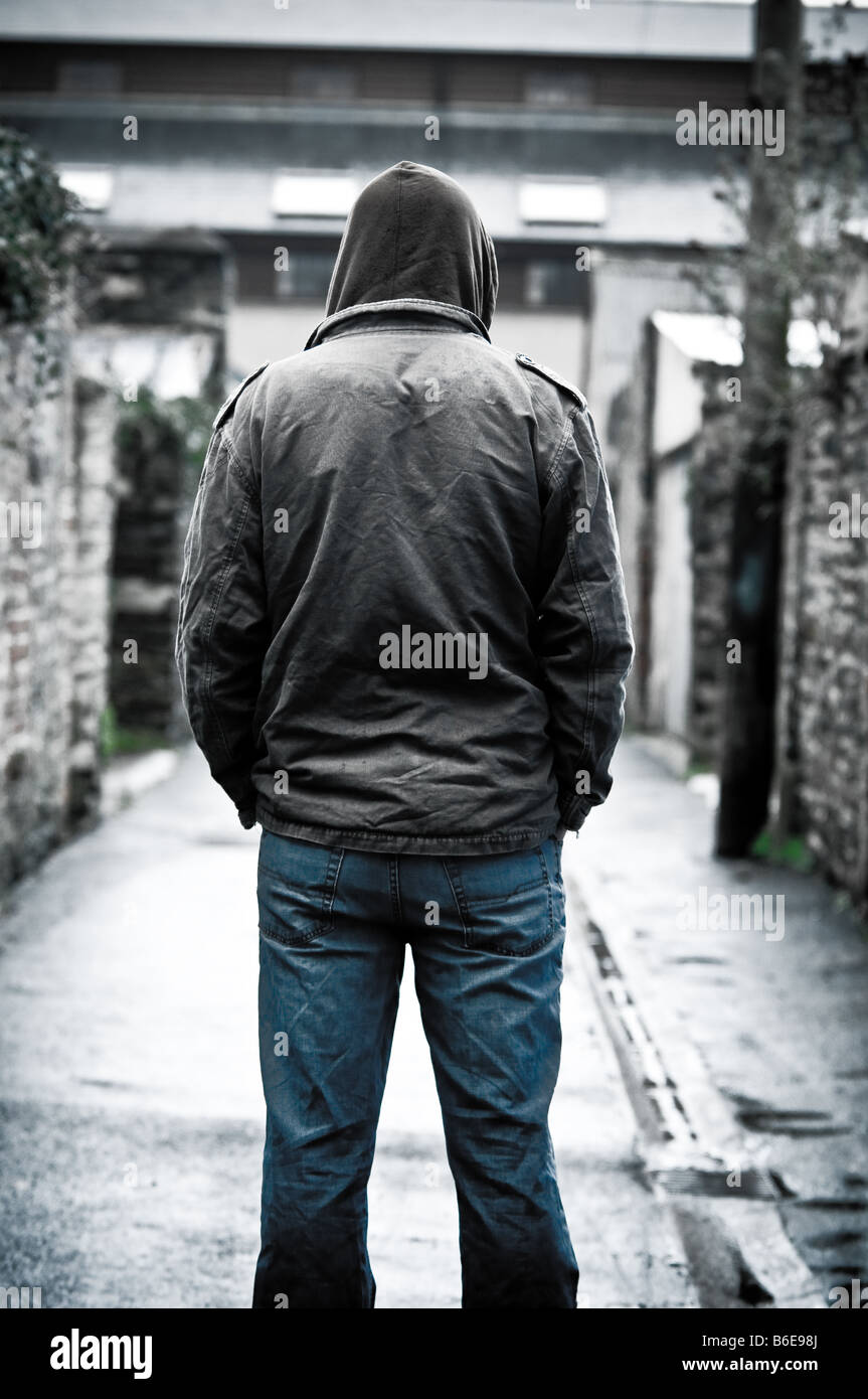 Jeune homme portant une veste seule et isolée dans une ruelle dans une ville vue de derrière, vue arrière Banque D'Images