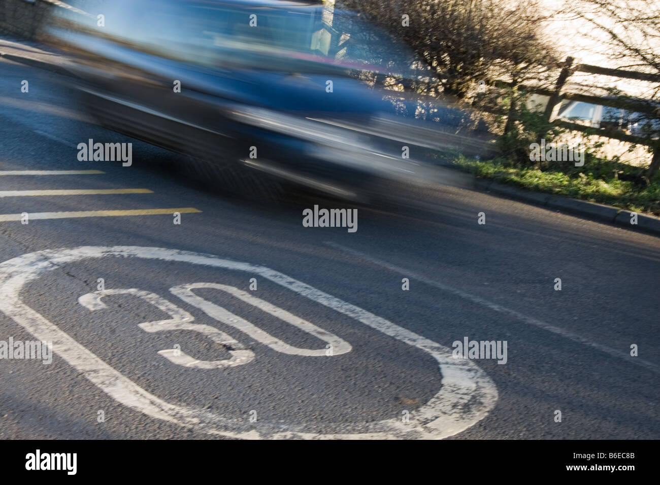 Une voiture dans le motion blur en passant à 30 milles à l'heure limite de vitesse britannique situé dans le road sign Banque D'Images
