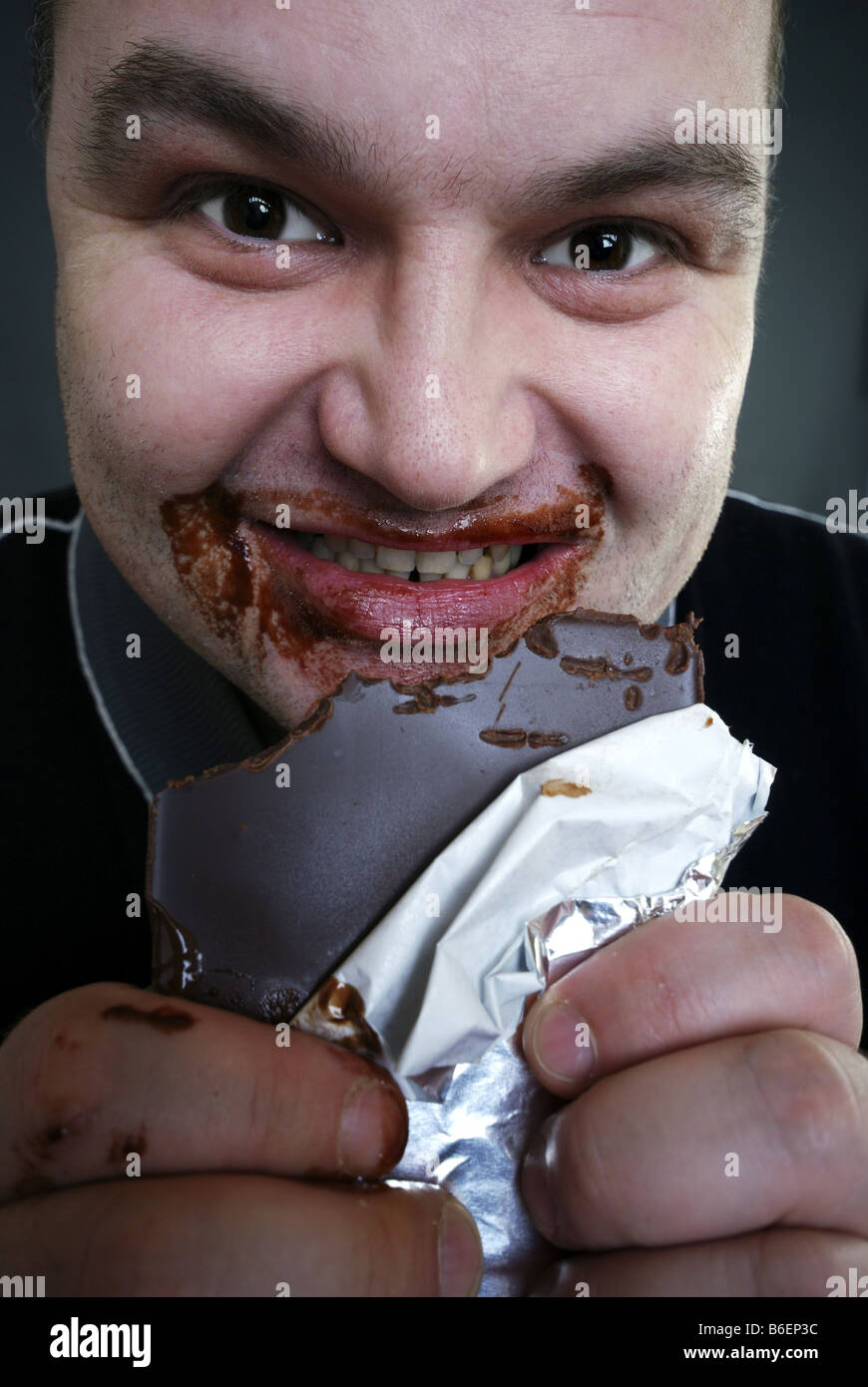 Homme besmeared avec barre de chocolat manger du chocolat Banque D'Images